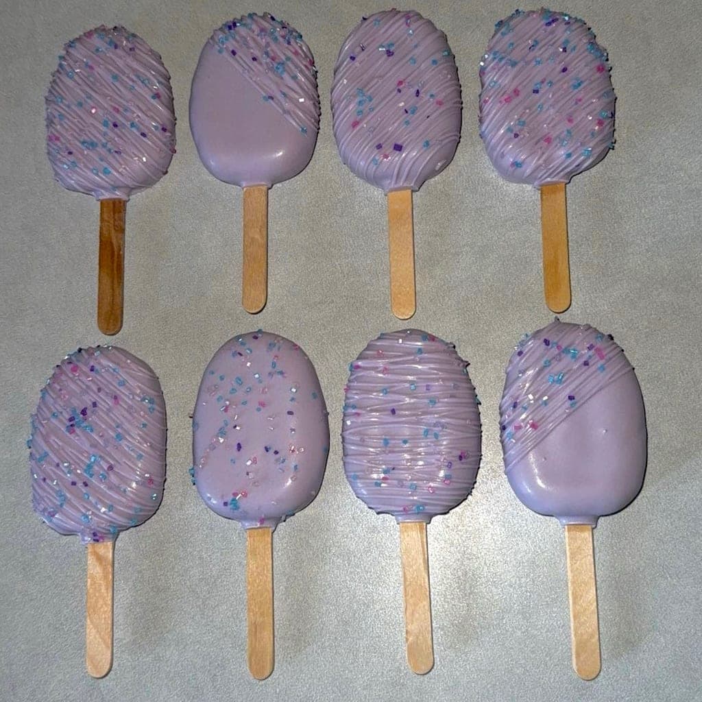 Elegant lilac cakesicles with fine drizzle and sparkling sprinkles