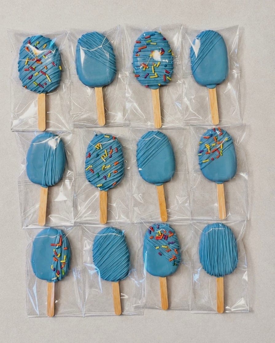 Blue-coated cakesicles topped with rainbow sprinkles
