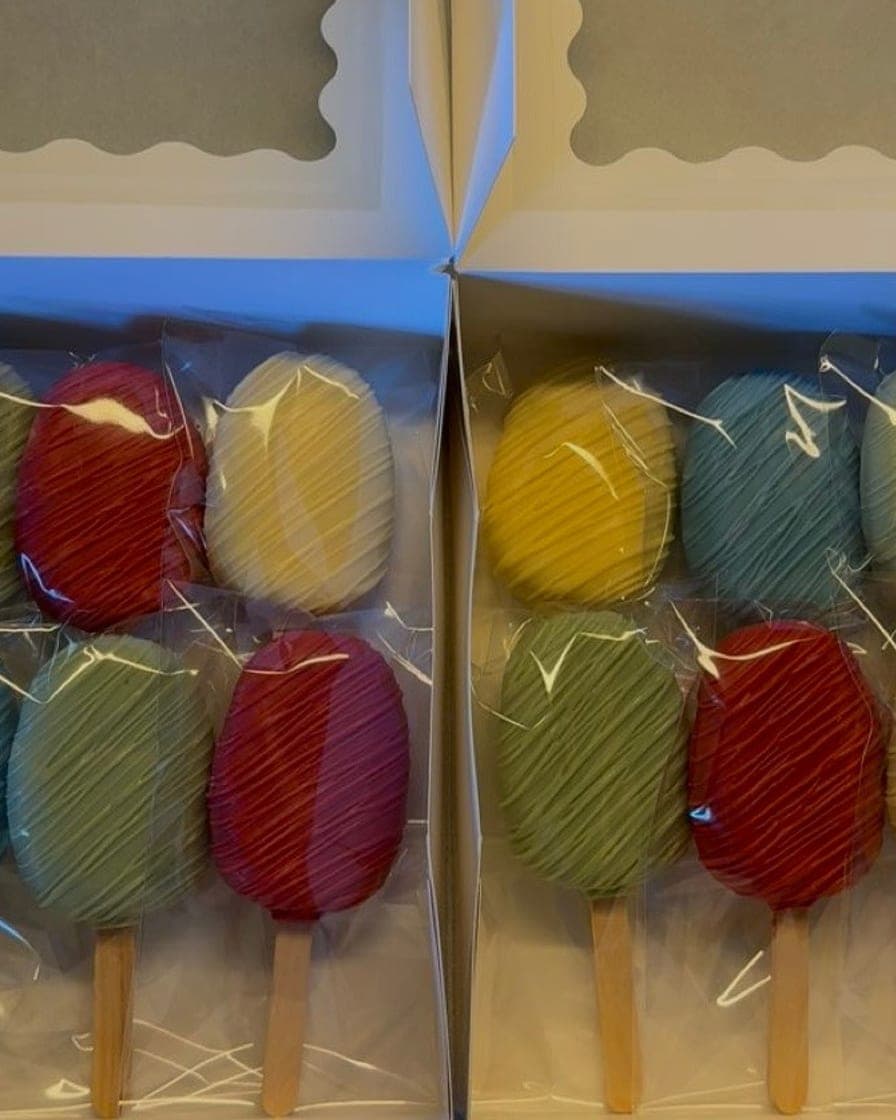 Boxes of colorful cakesicles in red, yellow, green, and blue