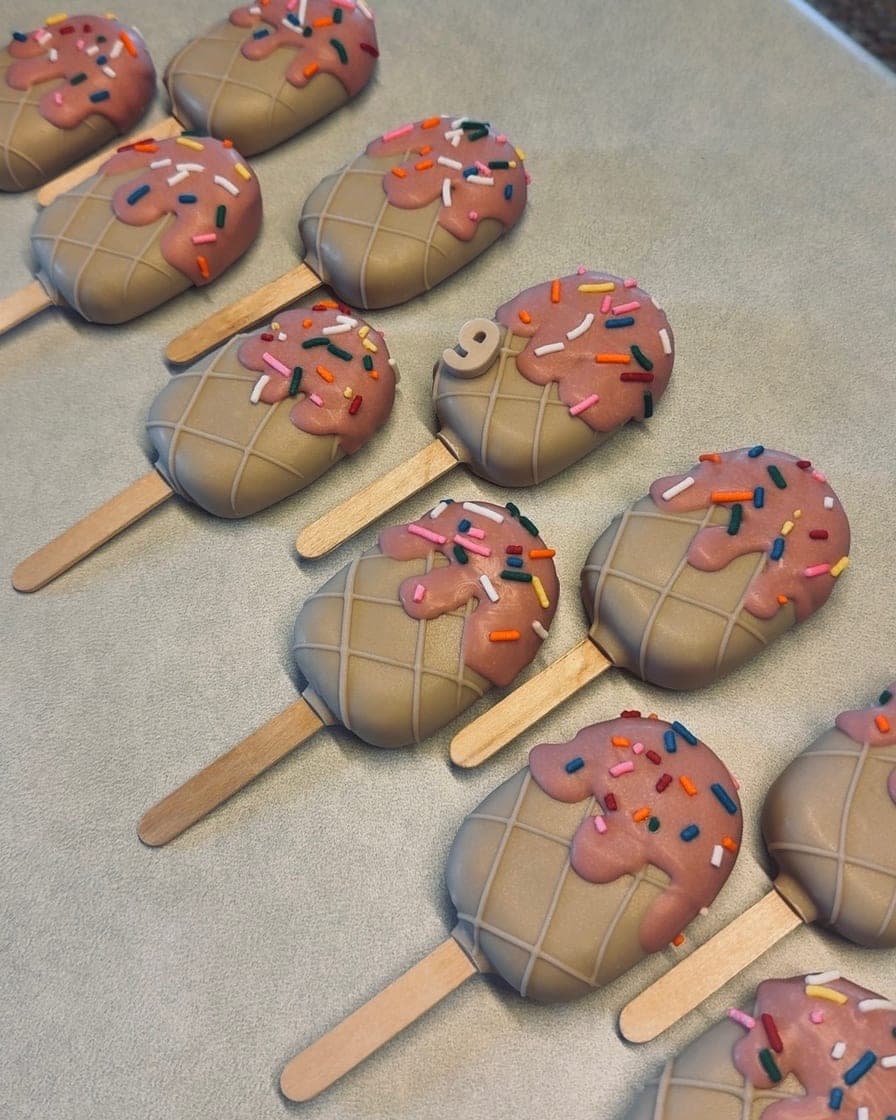 Cakesicles with pink drizzle tops and rainbow sprinkles