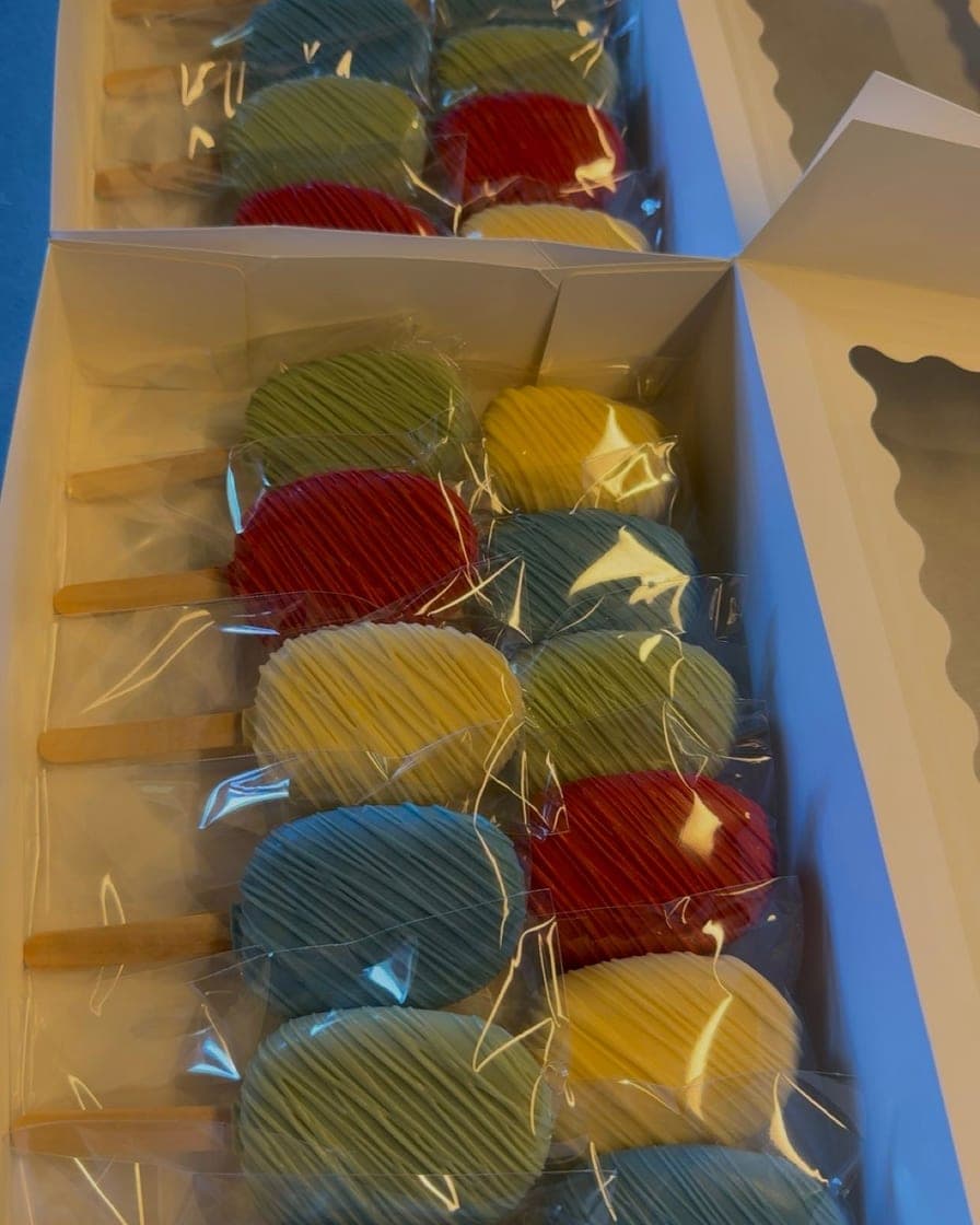 Boxes of brightly colored cakesicles in red, yellow, green, and blue