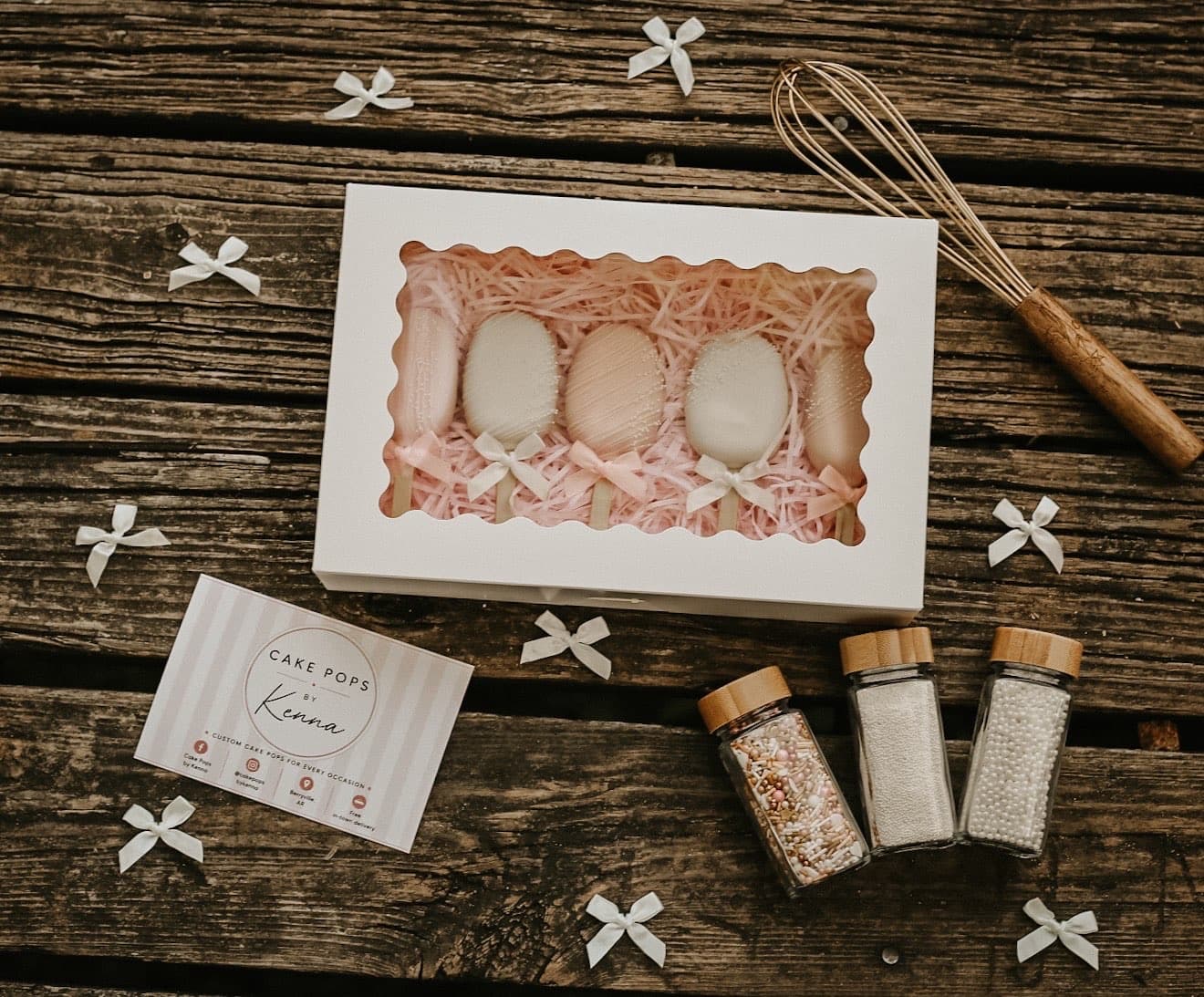 Flatlay of packaged cake pops with sprinkles and a whisk